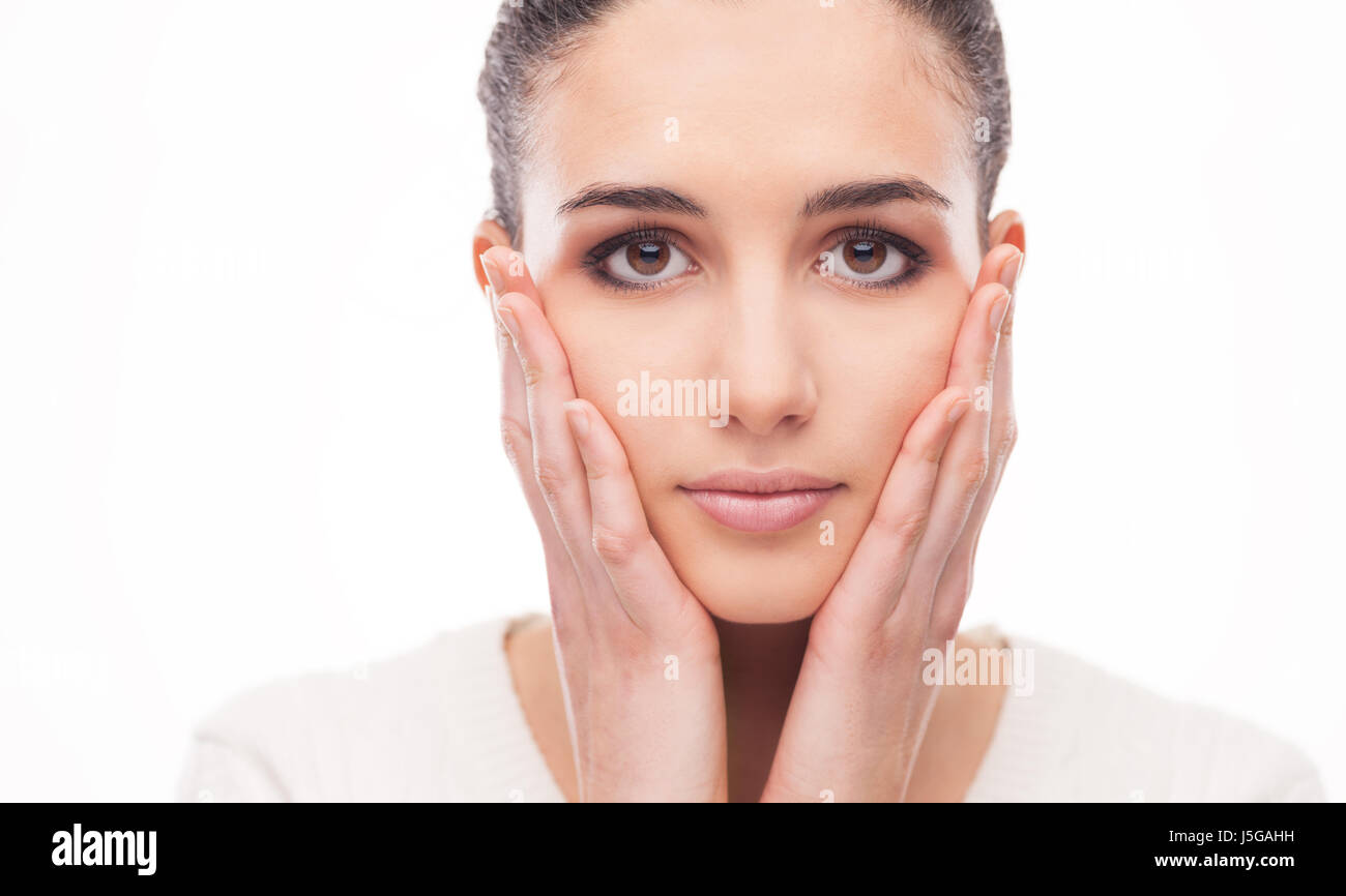 Beautiful relaxed woman touching her cheeks and posing on white background Stock Photo