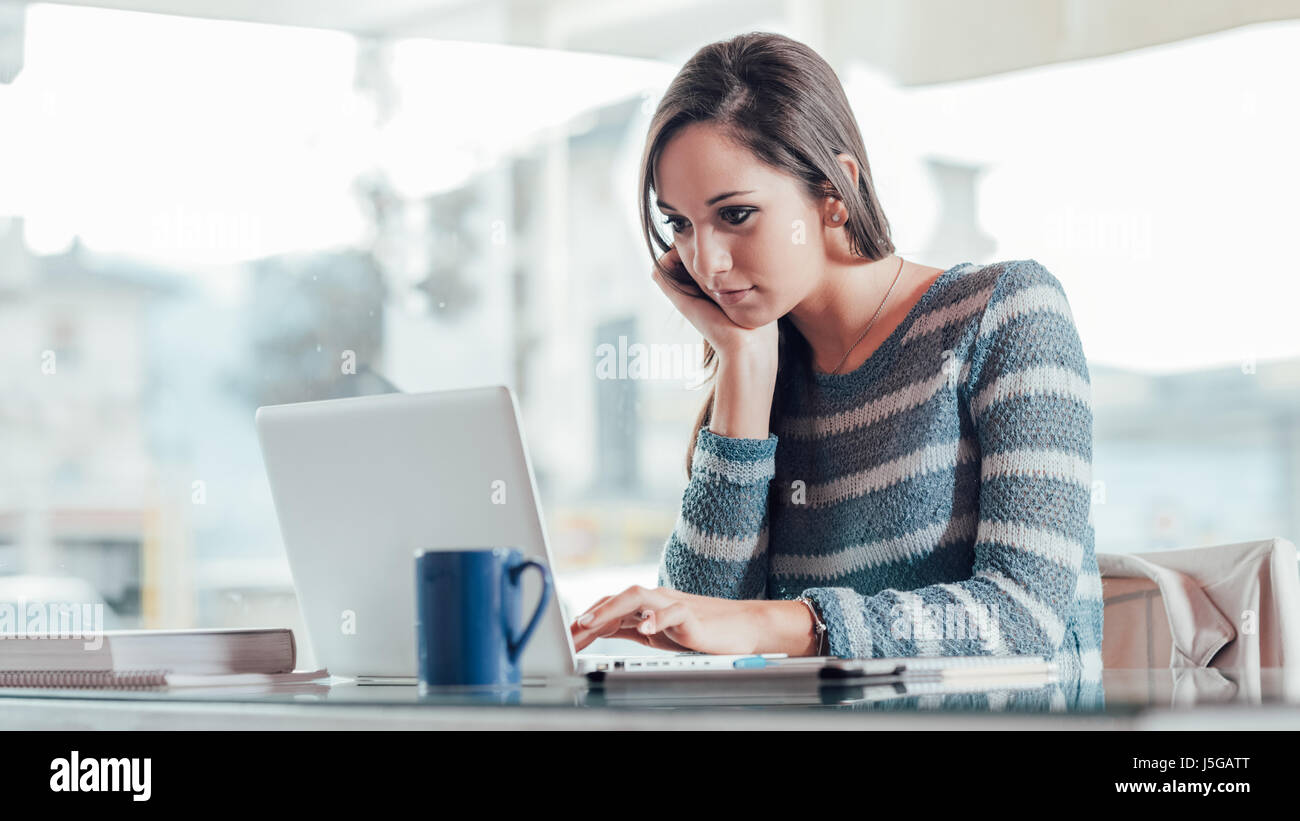 Busy young woman working with her laptop on a desk Stock Photo - Alamy