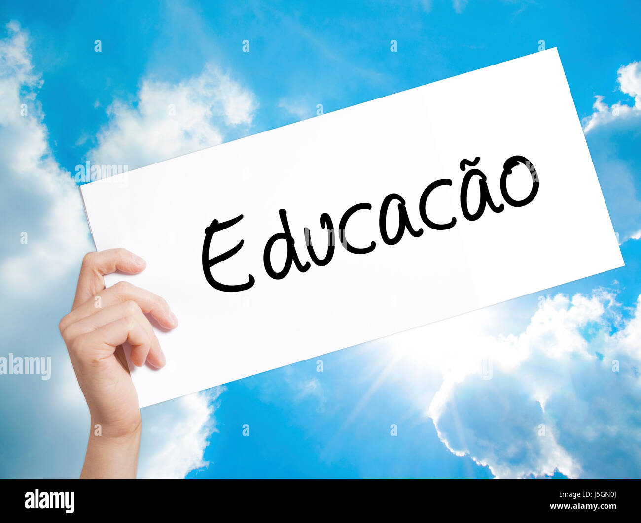 Education (Educacao in Portuguese) Sign on white paper. Man Hand Holding Paper with text. Isolated on sky background.  Business concept. Stock Photo Stock Photo