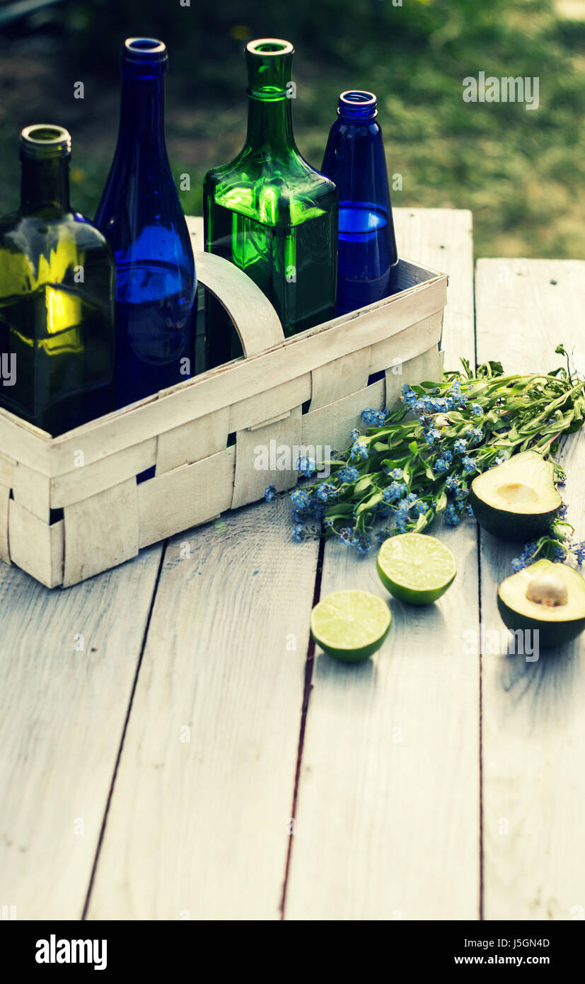 Four bottles of drinks in a white basket and fruits on the white table Stock Photo