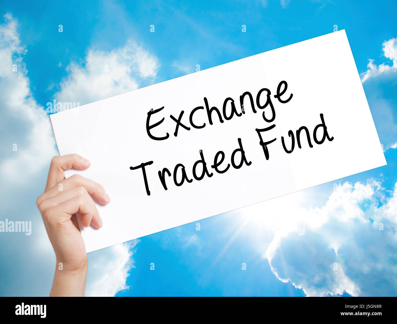 Exchange Traded Fund Sign on white paper. Man Hand Holding Paper with text. Isolated on sky background.  Business concept. Stock Photo Stock Photo