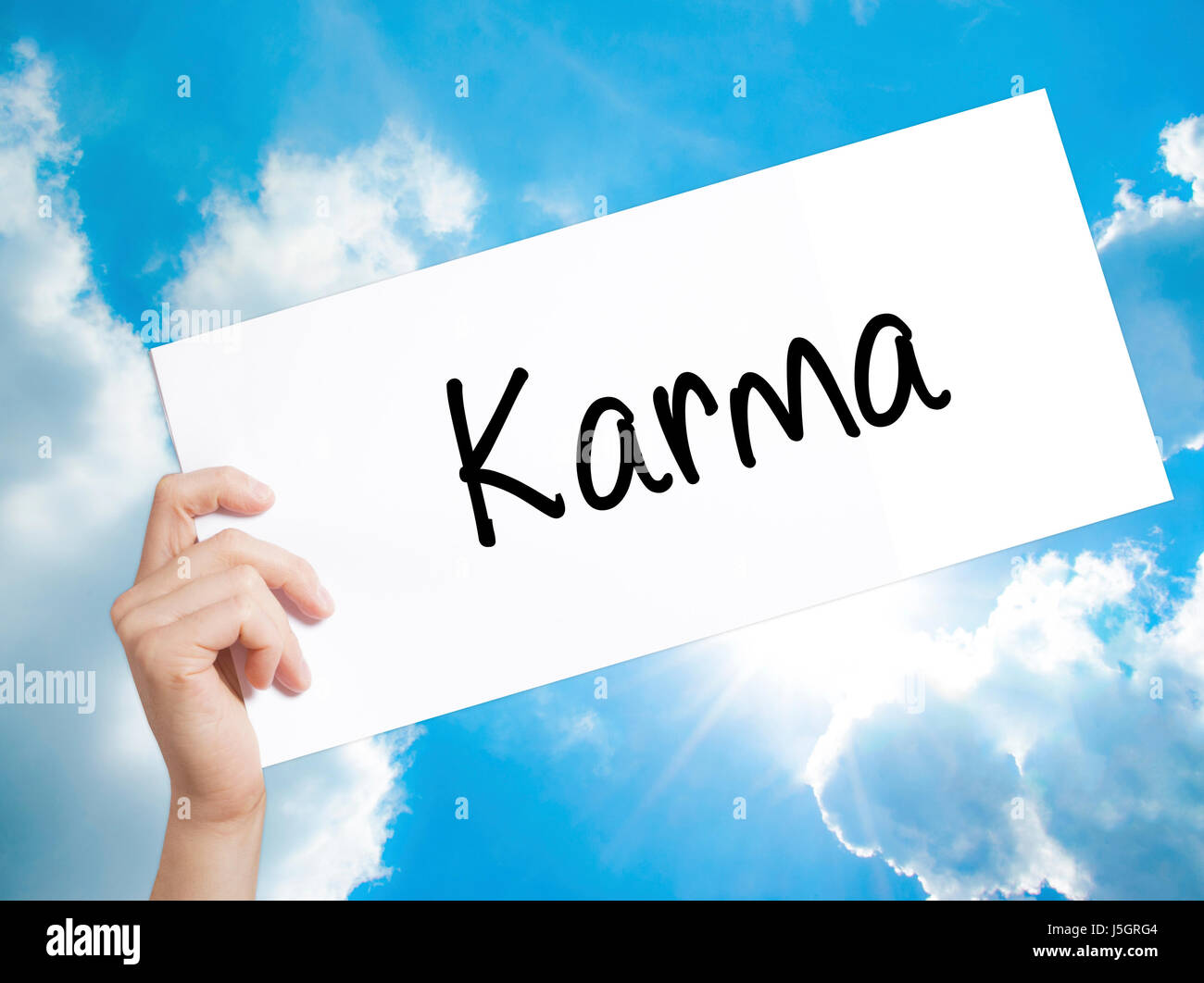 Karma  Sign on white paper. Man Hand Holding Paper with text. Isolated on sky background.  Business concept. Stock Photo Stock Photo