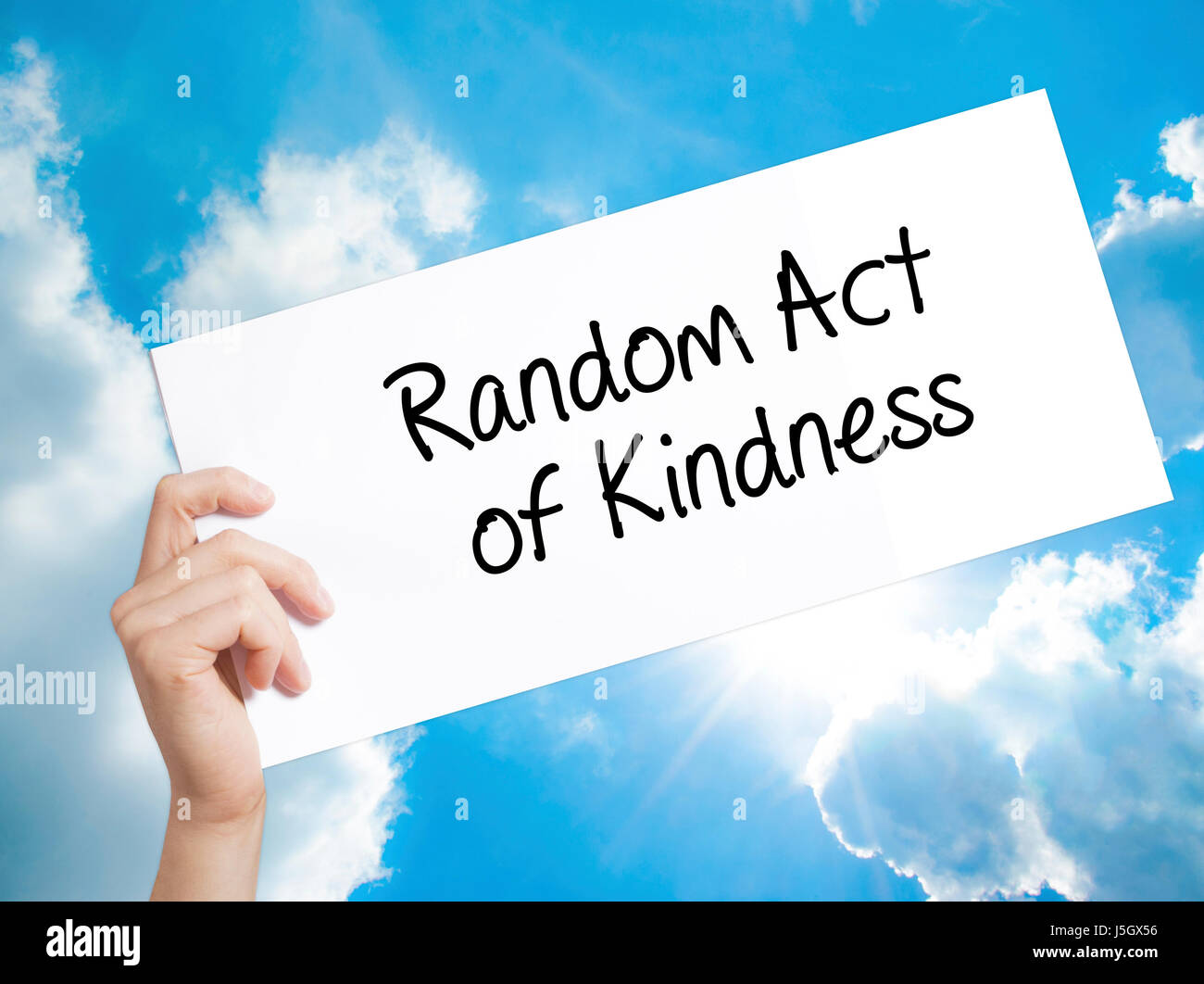 Random Act of Kindness Sign on white paper. Man Hand Holding Paper with text. Isolated on sky background.   Business concept. Stock Photo Stock Photo