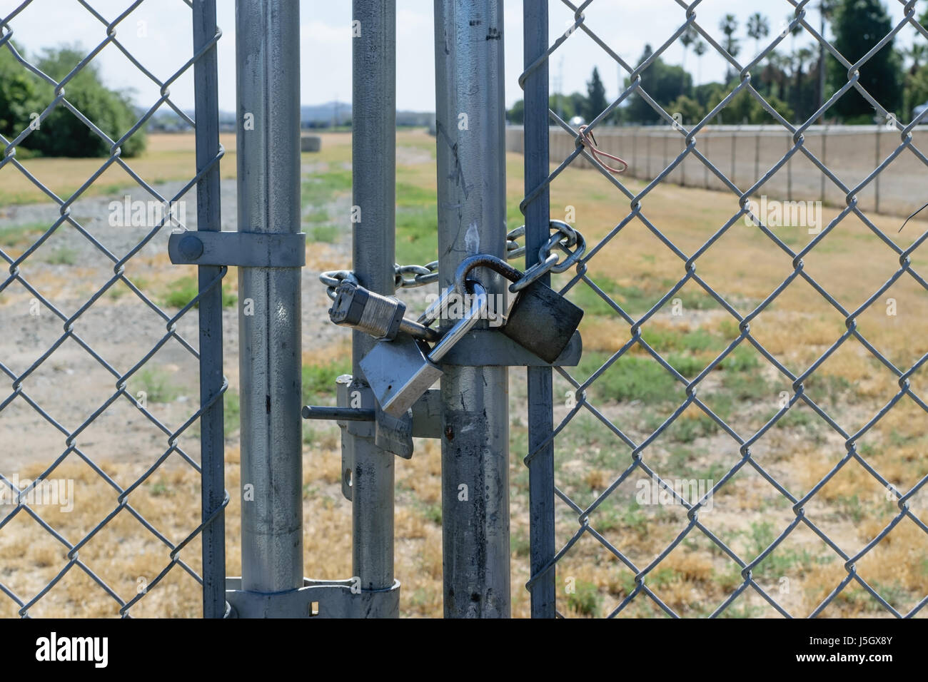 Three locks secure gate on fence Stock Photo