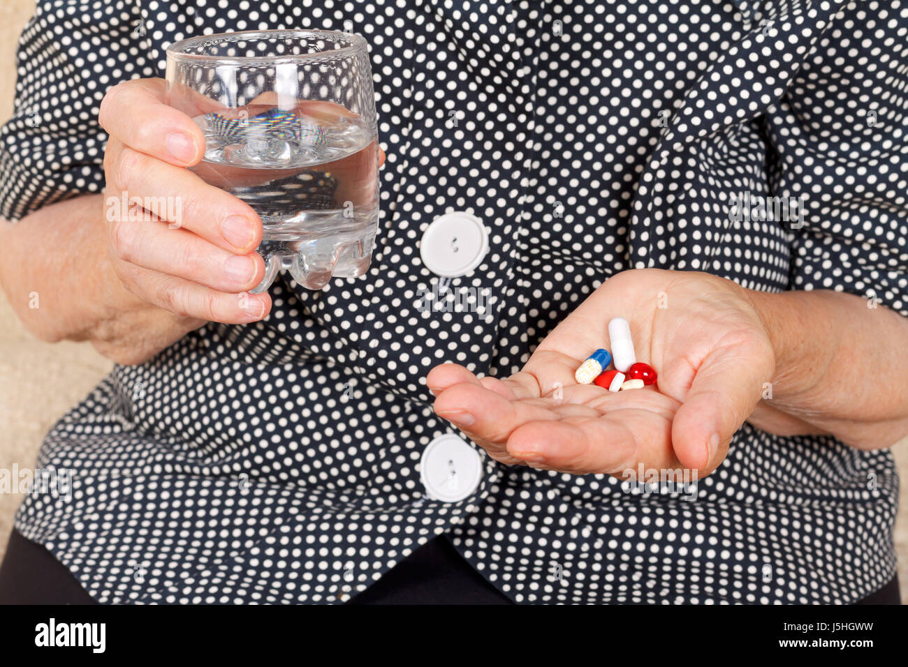 Picture of a senior woman pills holding pills and glass of water Stock Photo