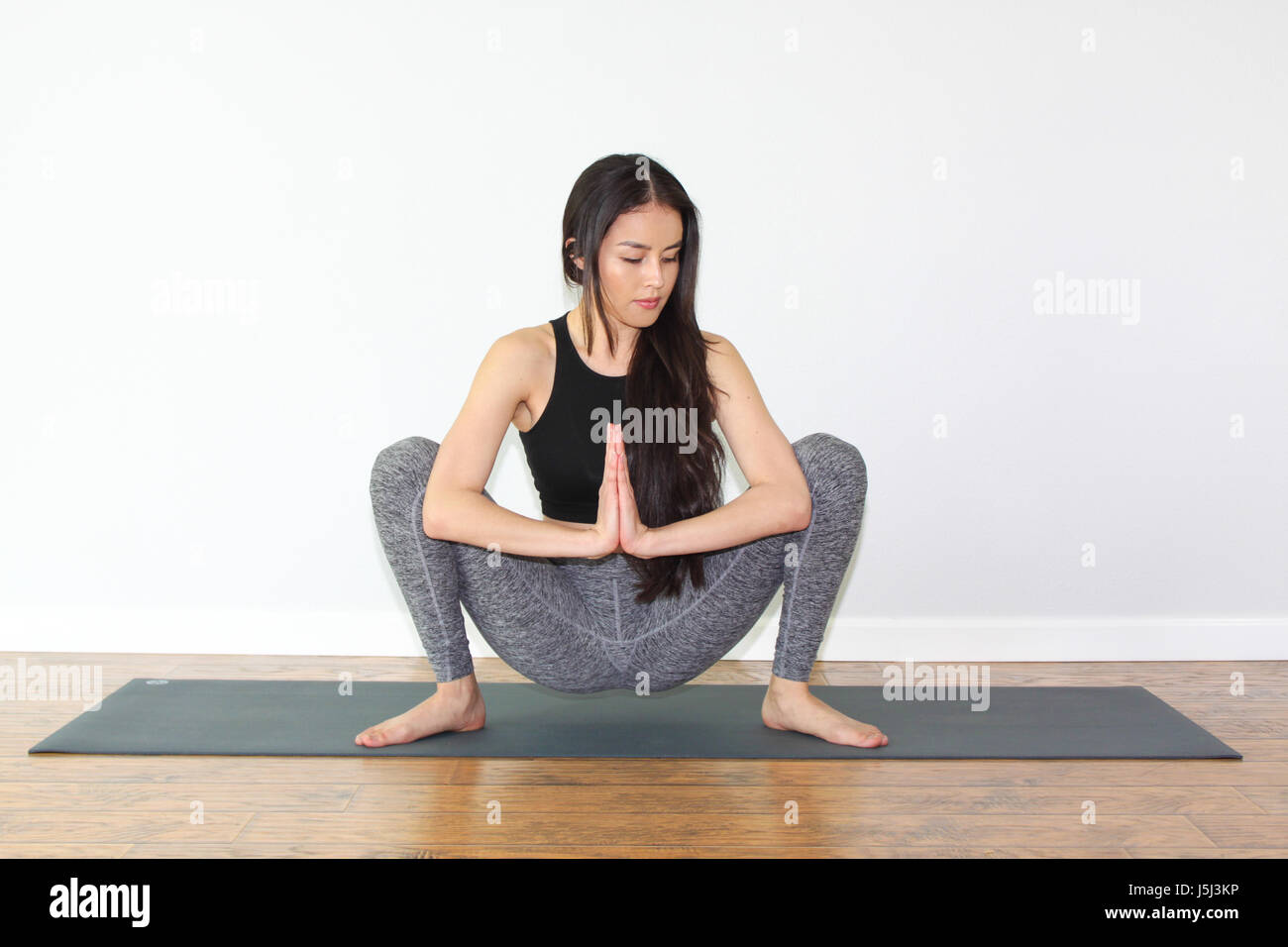 Beautiful woman doing a yoga pose called squat pose, or malasana pose. Stock Photo