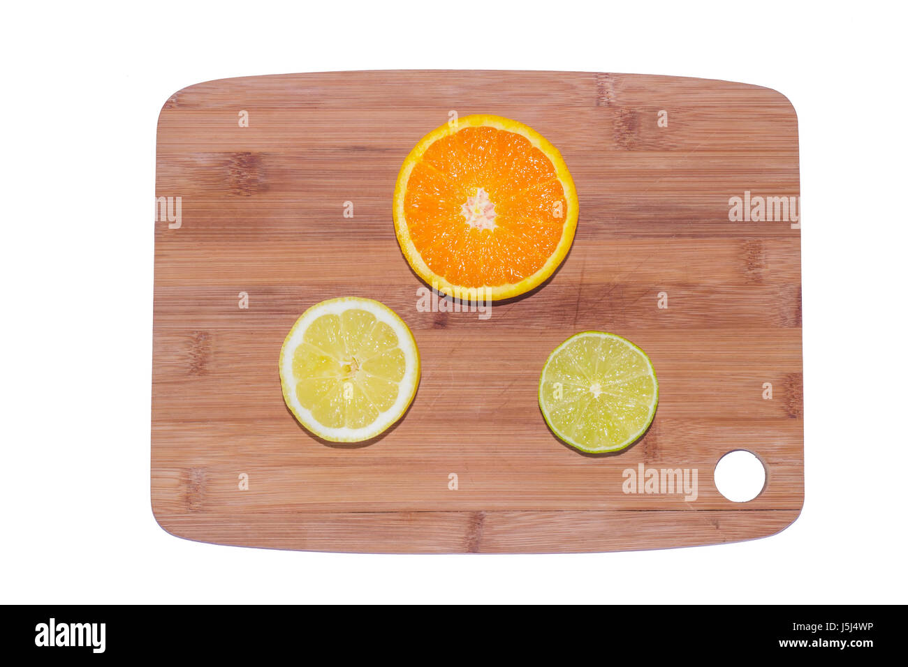 A selection of chopped oranges, lemons and limes on a wooden board on white background. Stock Photo
