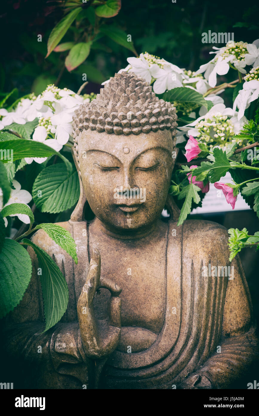 Garden buddha statue in a show garden at a flower show. UK.  Applied vintage retro filter Stock Photo