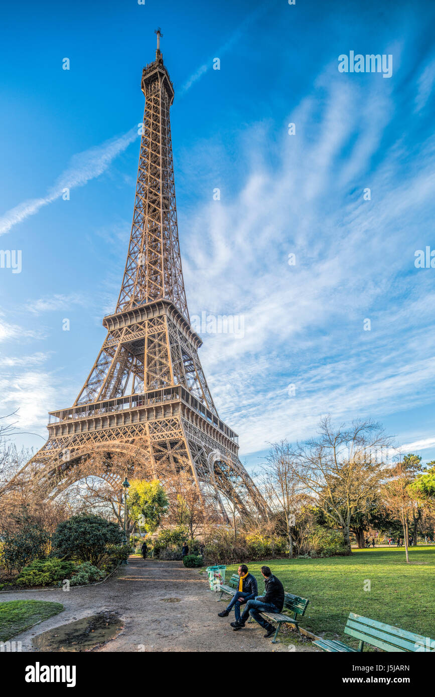 Two men sitting on a bench in front of the Eiffel Tower, Paris, France