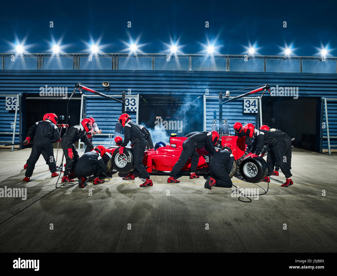 Pit crew working on formula one race car in pit stop Stock Photo