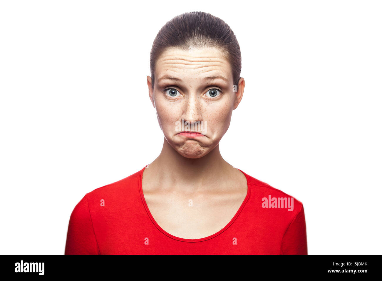 I don't know. portrait of funny confused woman in red t-shirt with freckles. looking at camera, studio shot. isolated on white background. Stock Photo
