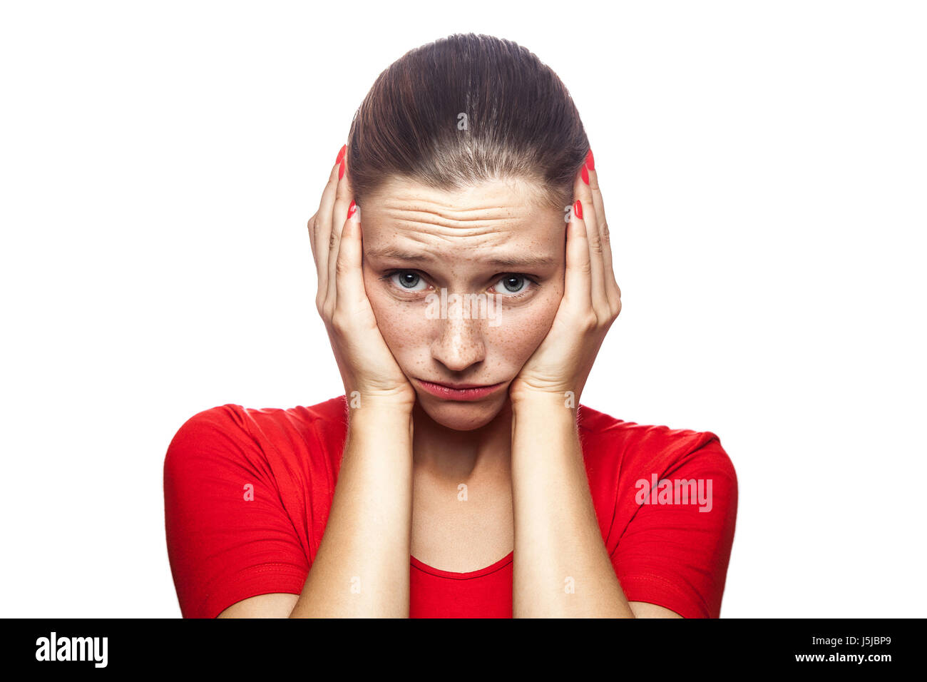 Portrait of worried scared woman in red t-shirt with freckles. looking at camera, studio shot. isolated on white background. Stock Photo