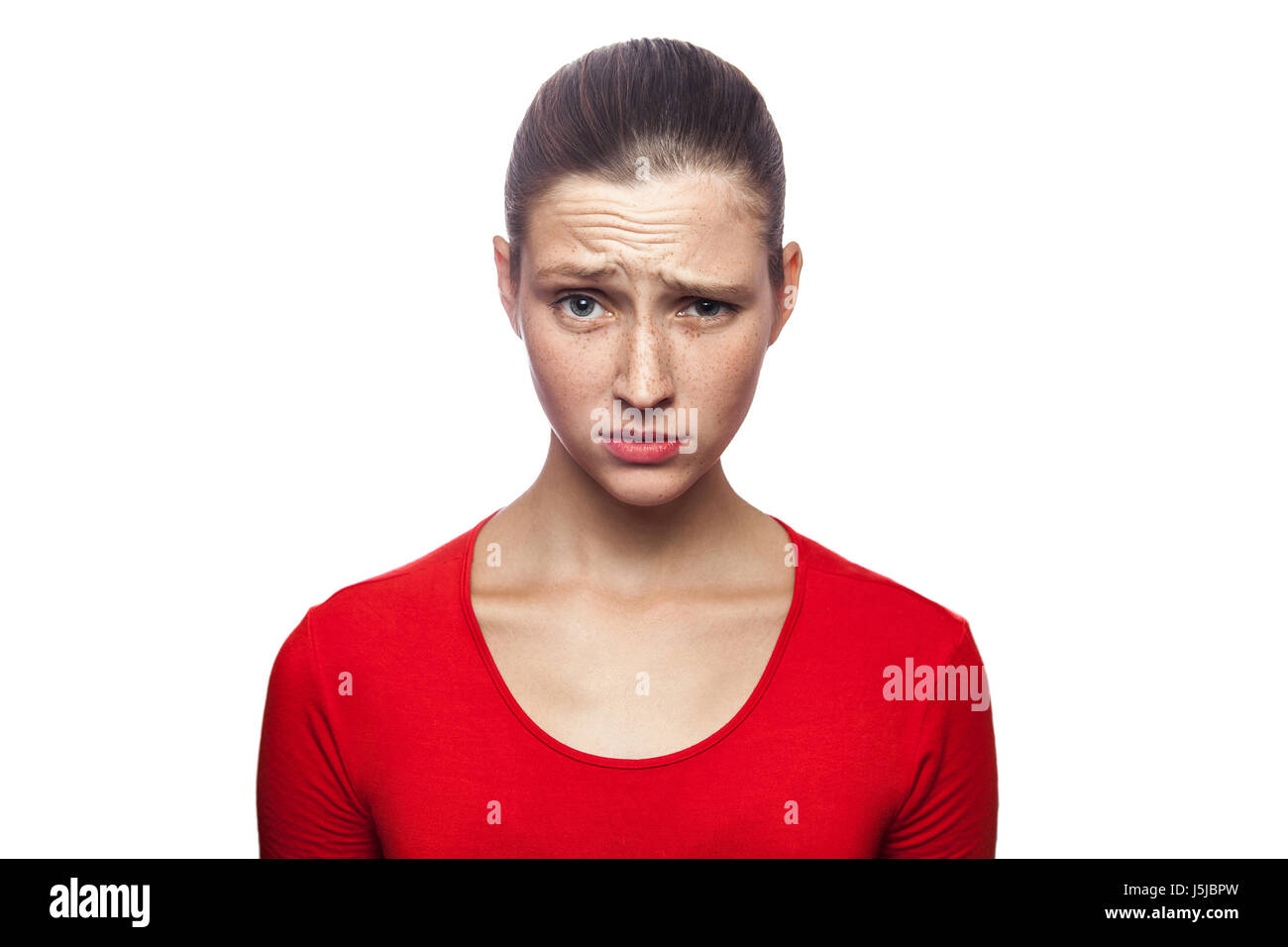I don't know. portrait of funny confused woman in red t-shirt with freckles. looking at camera, studio shot. isolated on white background. Stock Photo