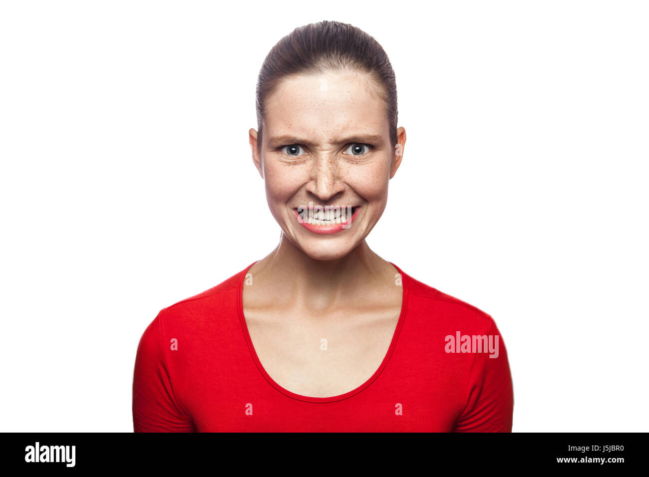 Portrait of worried angry woman in red t-shirt with freckles. looking at camera and screaming, studio shot. isolated on white background. Stock Photo