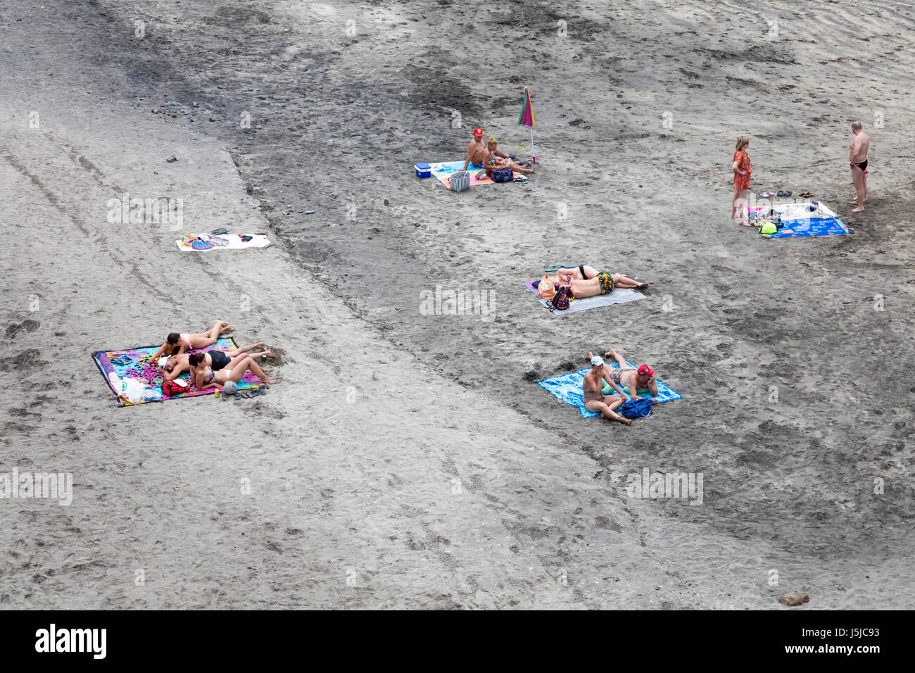People sunbathing on a volcanic beach in Tenerife, Spain Stock Photo