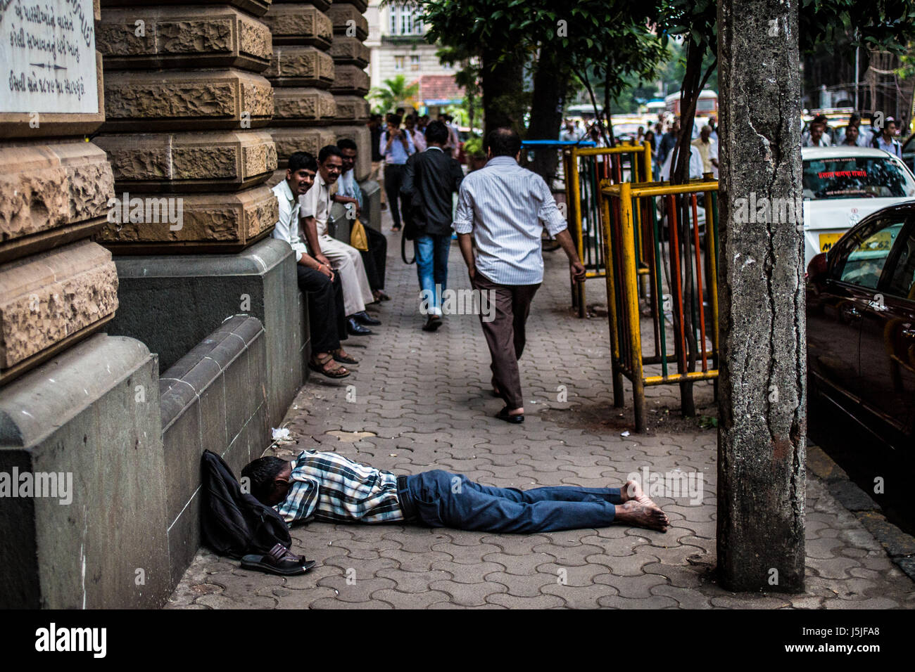 An Indian man taking a nap in the middle of the street during the hot hours in Mumbai, India Stock Photo