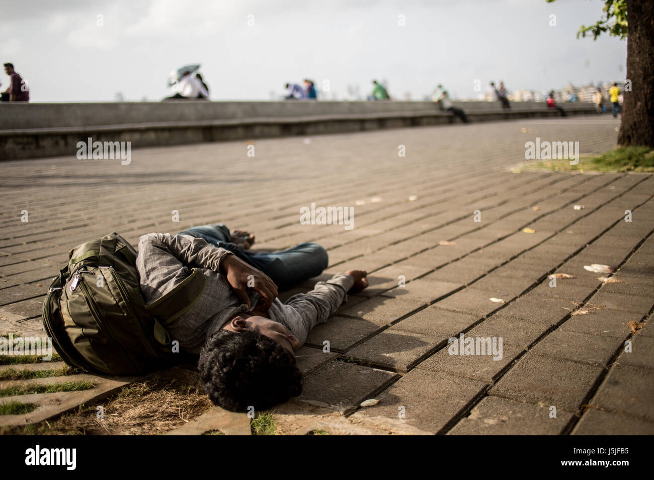 A student taking a little nap on the road at lunch time in Mumbai, India. Stock Photo