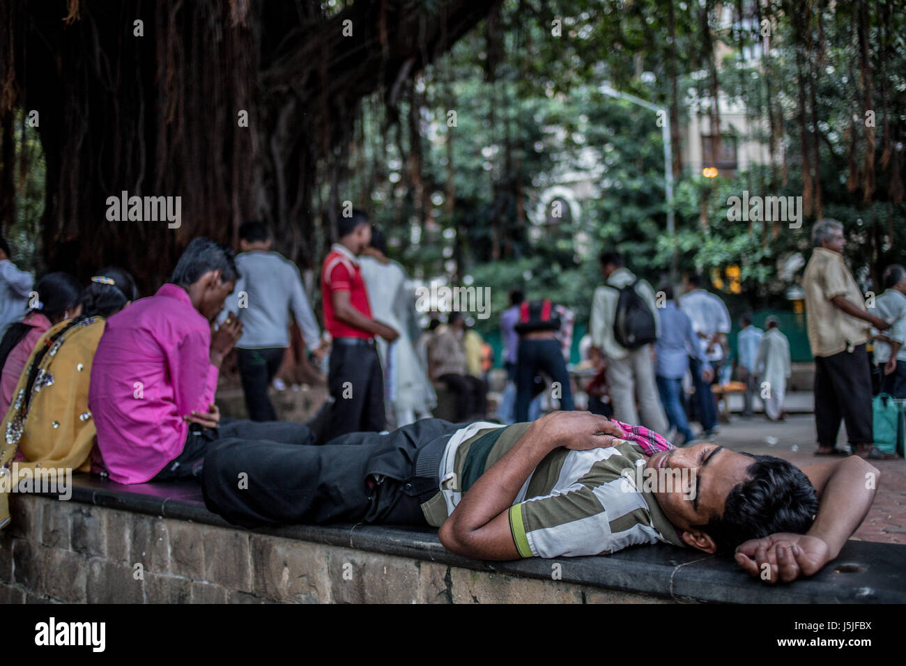 A man asleep during a hot day on a ledge near the Gateway of India monument in Mumbai. Stock Photo