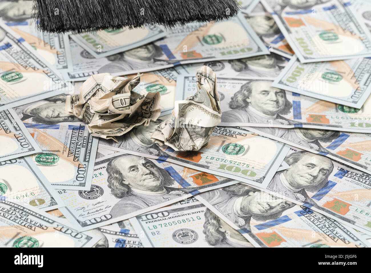 A garbage brush sweeps away old crumpled money from new bills laid out