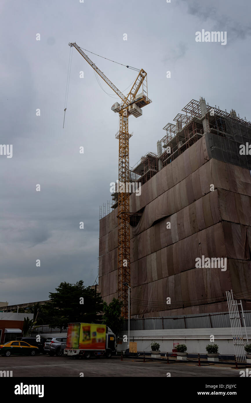 Tower cranes at construction site against cloudy sky Stock Photo - Alamy