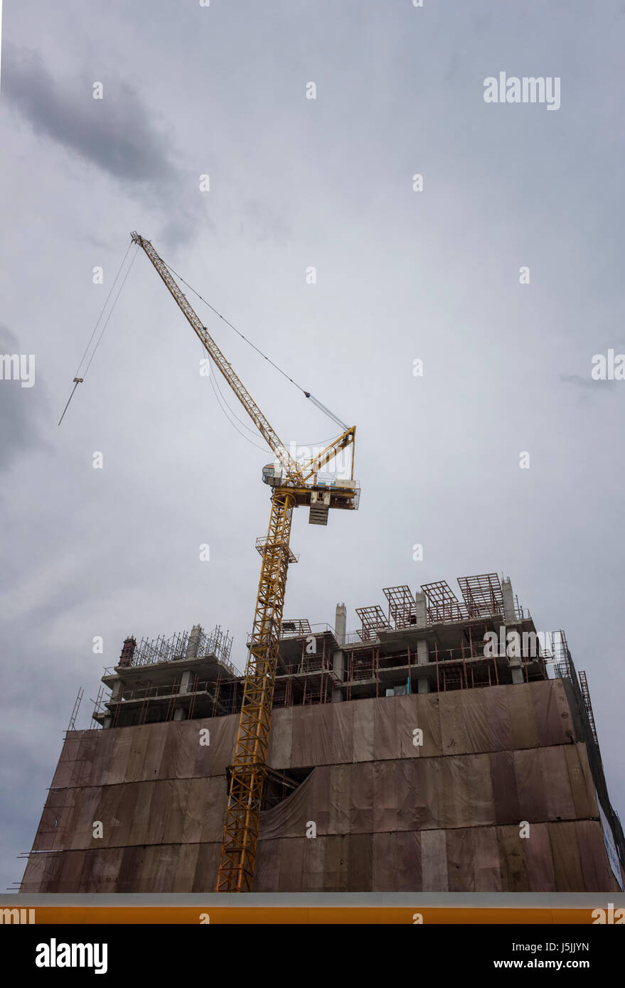 Tower cranes at construction site against cloudy sky Stock Photo - Alamy