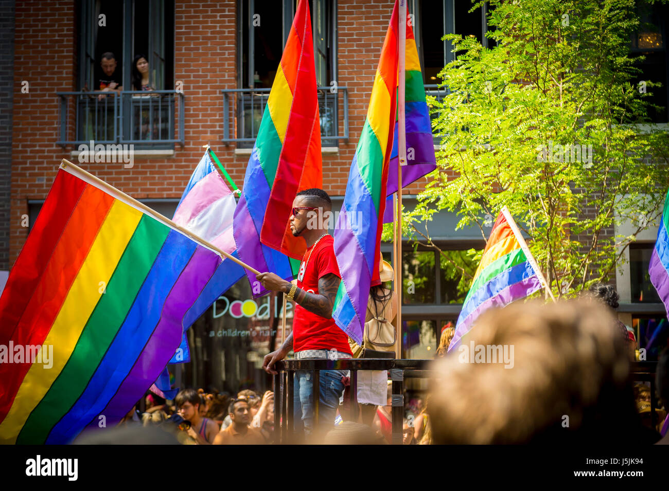 NEW YORK CITY - JUNE 26, 2015: Supporters wave rainbows flags on the sidelines of the annual Pride Parade as it passes through Greenwich Village. Stock Photo