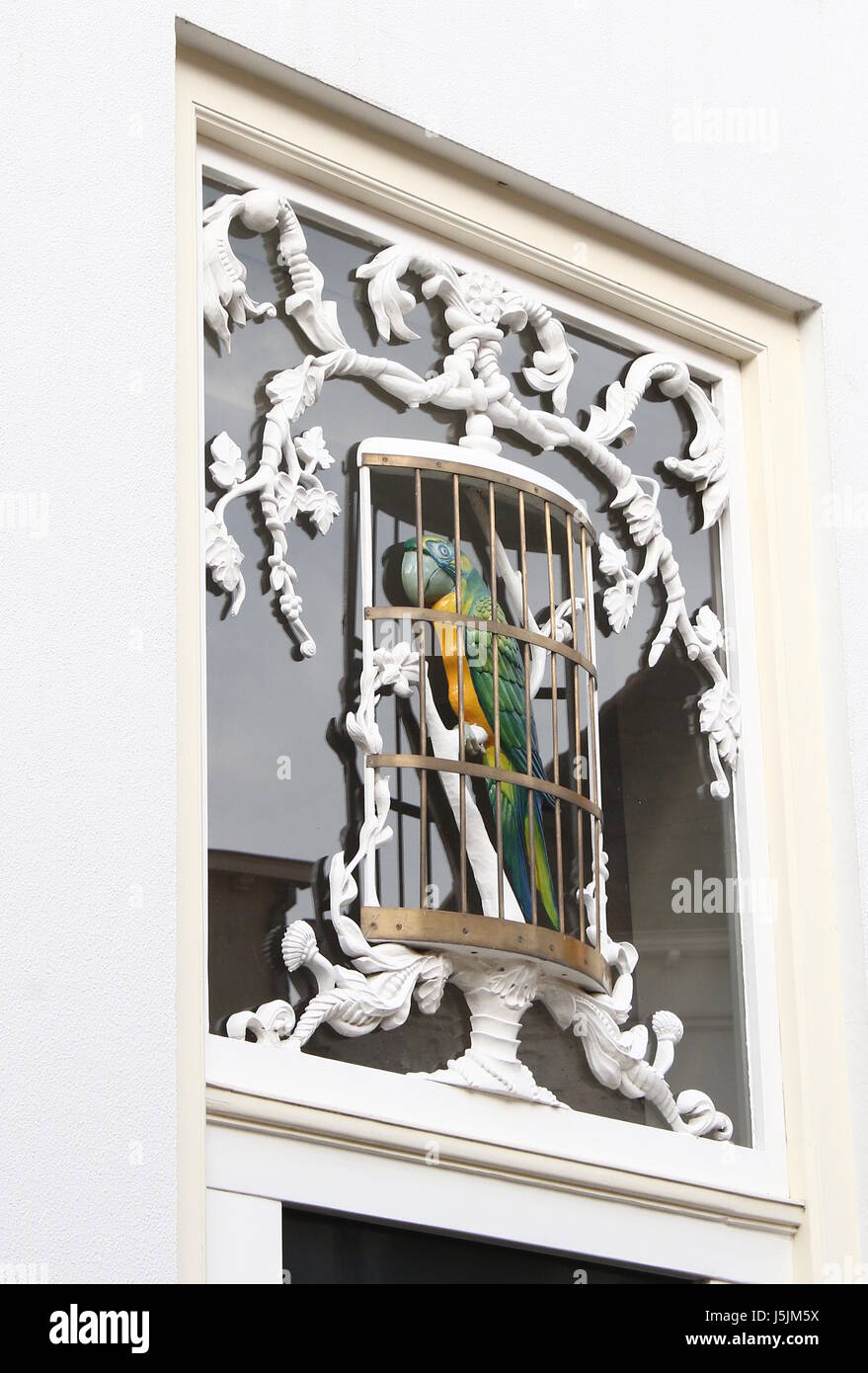 Ornamental wood carved Blue and Gold macaw in a cage, over a door in Bergstraat, city centre of Deventer, Netherlands. Stock Photo