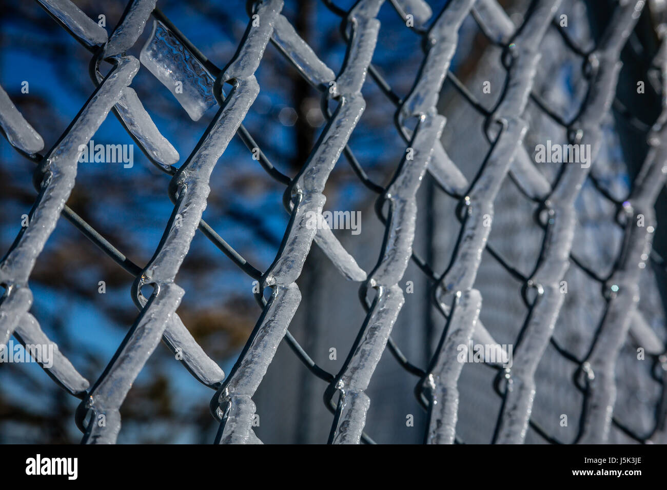 Ice on a chain link fence creates a wintry barrier. Stock Photo