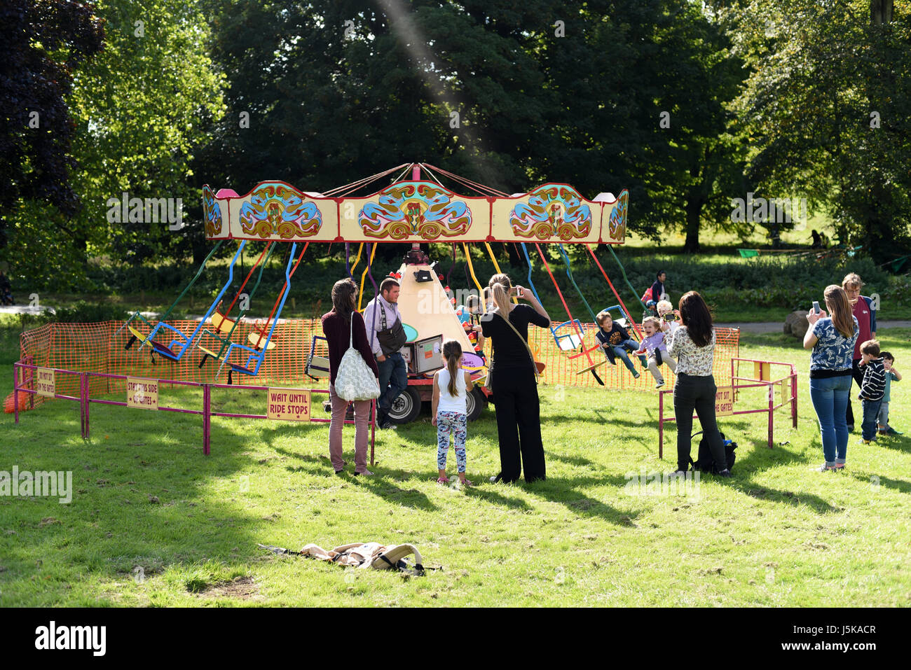 Parents watching children on old-fashioned fair ground ride, Brighton Apple Day, Stanmer Park, Brighton Stock Photo