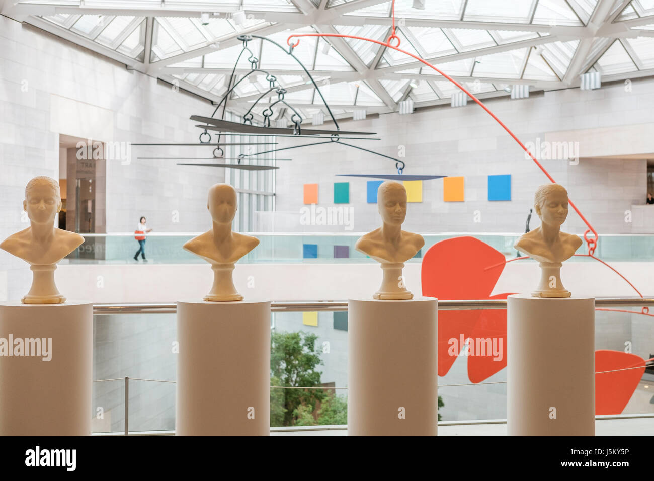 Atrium with Woman Walking and Art by Antoni, Kelly and Calder, National Gallery of Art, East Building, Washington, DC Stock Photo