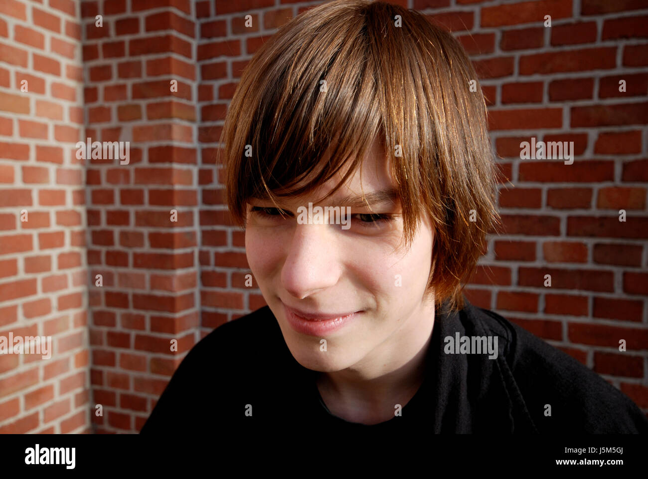 teen male masculine portrait outdoor grin brick wall yrs teenager puberty Stock Photo