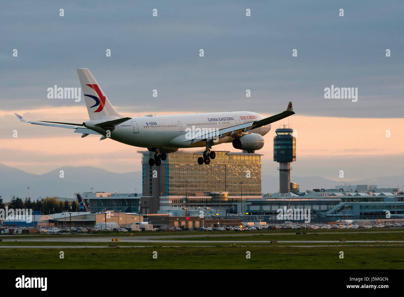China Eastern Airlines plane airplane landing Vancouver International Airport terminal exterior dusk twilight view Airbus A330 jetliner B-5936 Stock Photo
