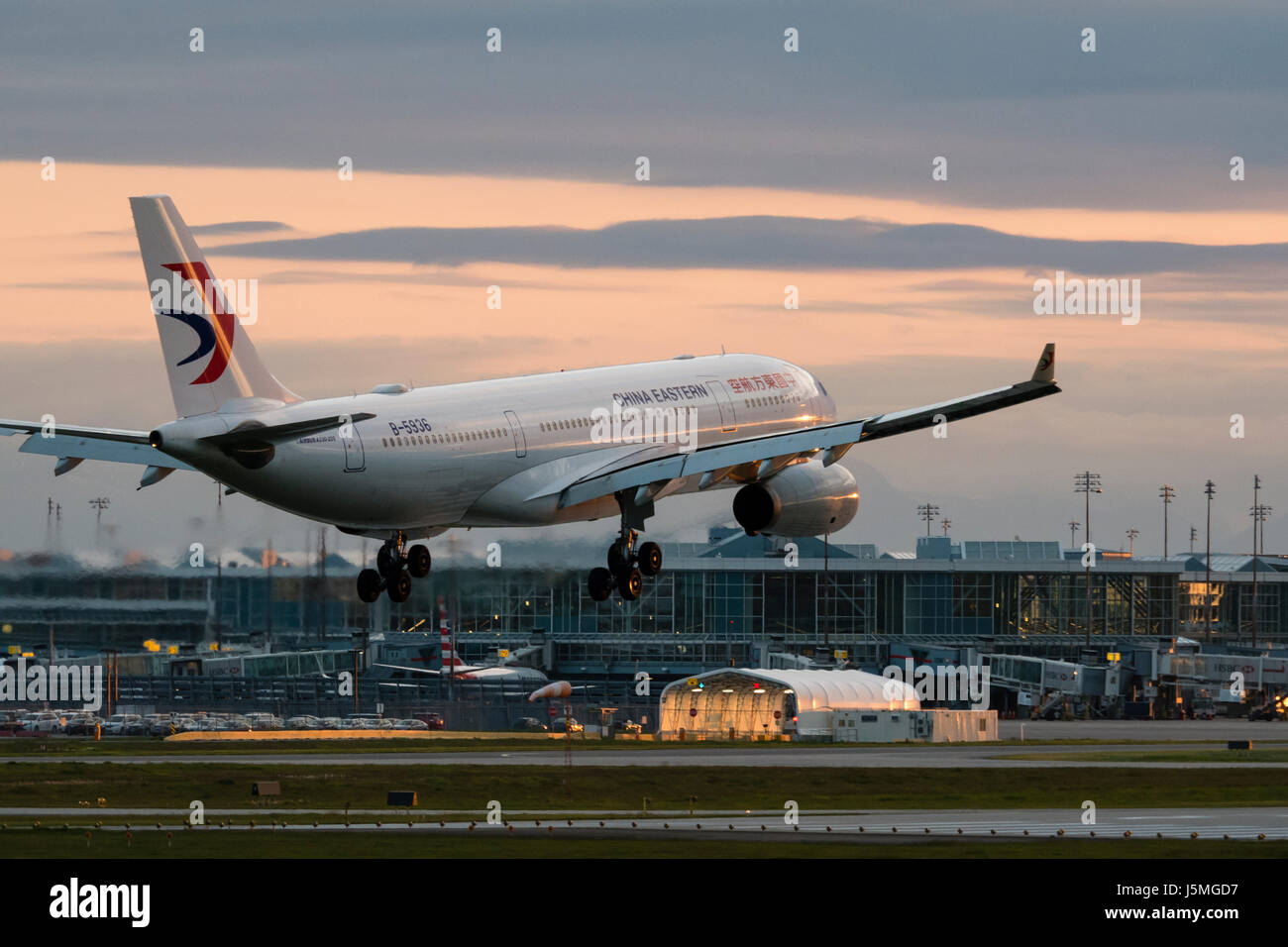 China Eastern Airlines plane airplane landing Vancouver International Airport terminal exterior dusk twilight view Airbus A330 jetliner B-5936 Stock Photo