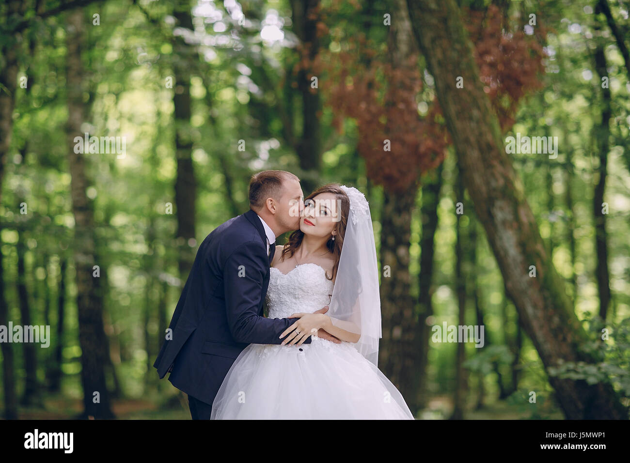 bride and groom walking in a green forest Stock Photo - Alamy