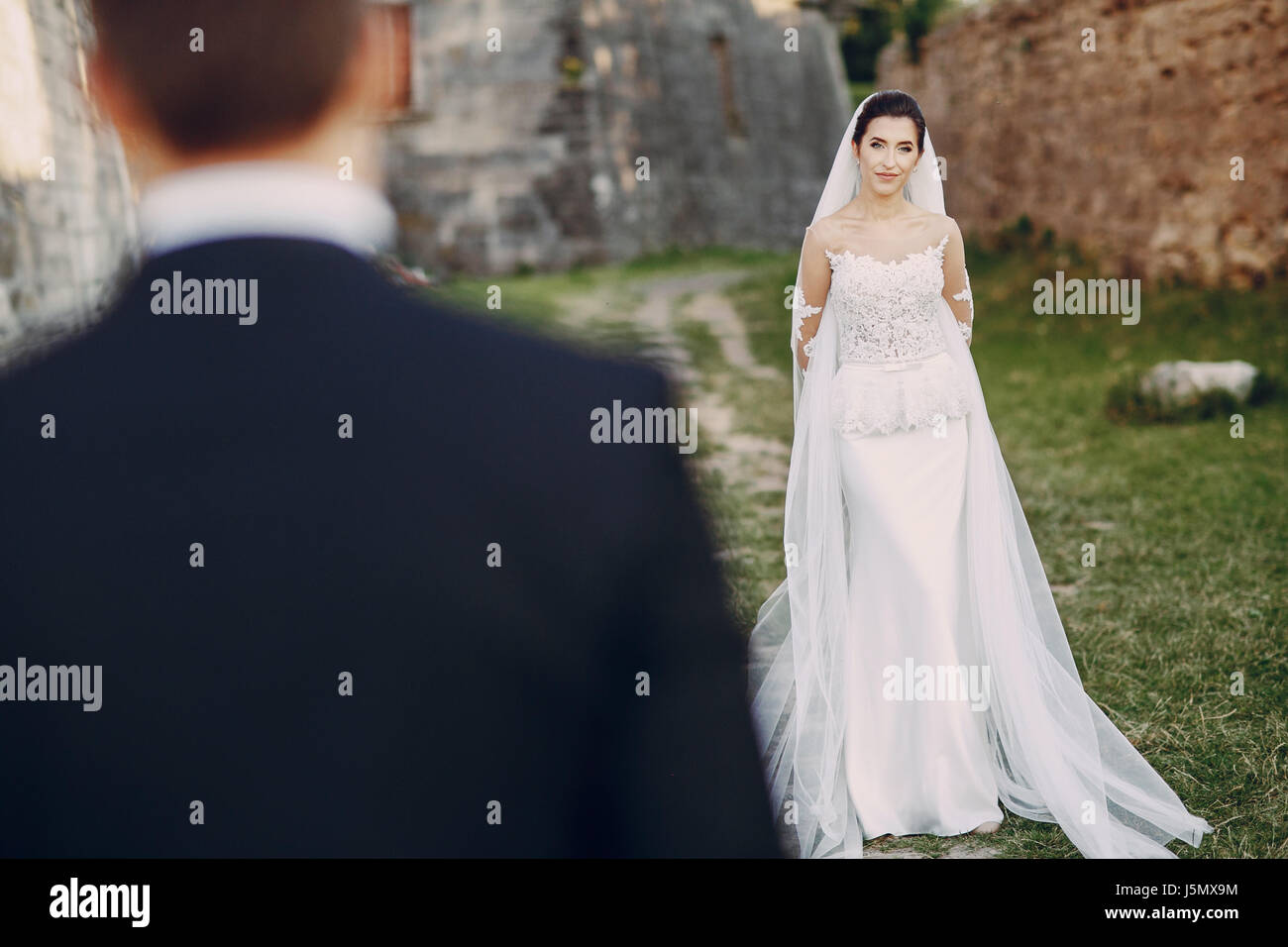 bride and groom standing on the footpath near the brick wall Stock ...
