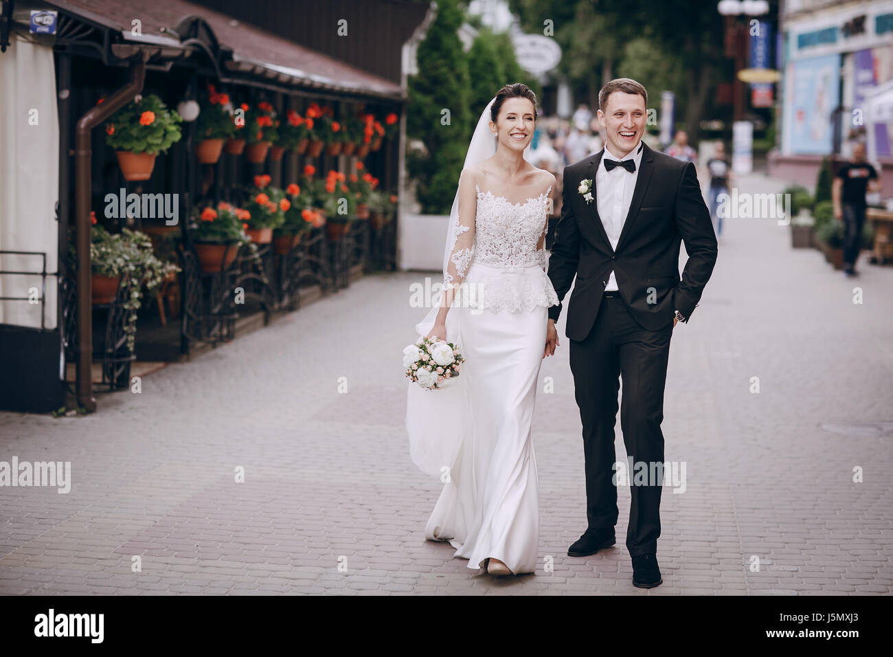 bride and groom walking around the city with a bouquet of flowers Stock ...