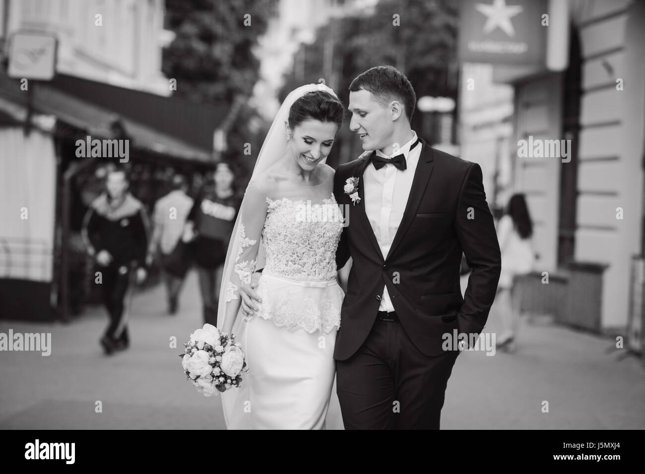 bride and groom walking around the city with a bouquet of flowers Stock ...