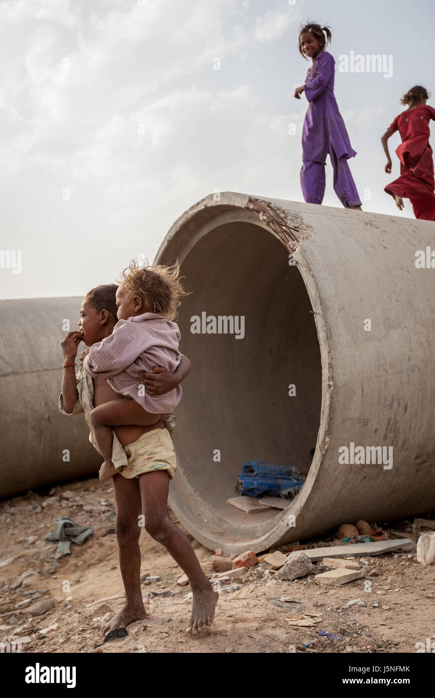 4 July 2009, Gurugram, Haryana, India : The children of local construction workers play among concrete drainage tubes on a construction site in Gurugr Stock Photo