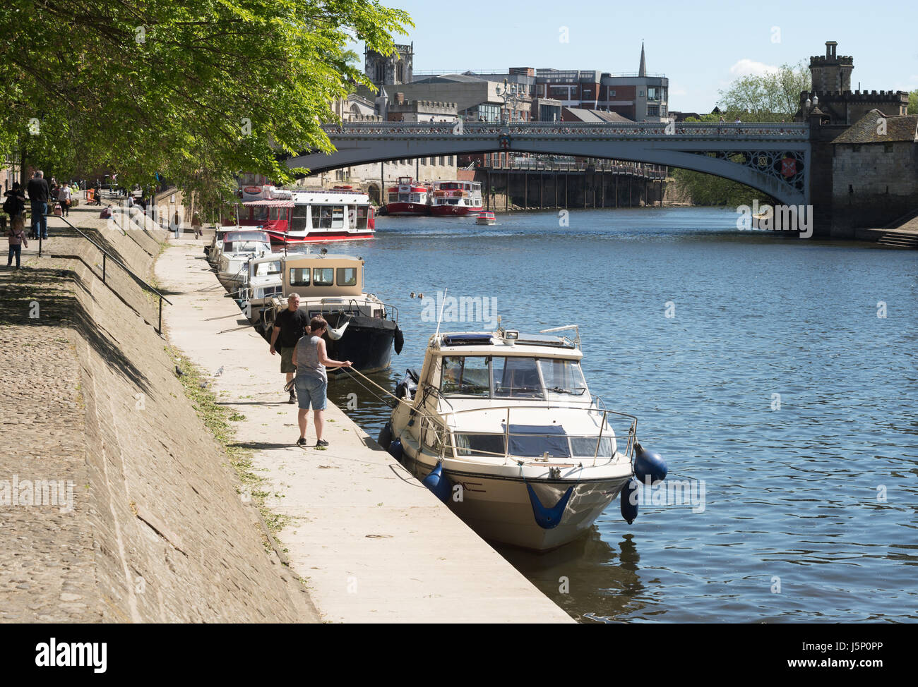 A couple mooring a boat on the riverside near Lendal Bridge, York, North Yorkshire, England, UK Stock Photo