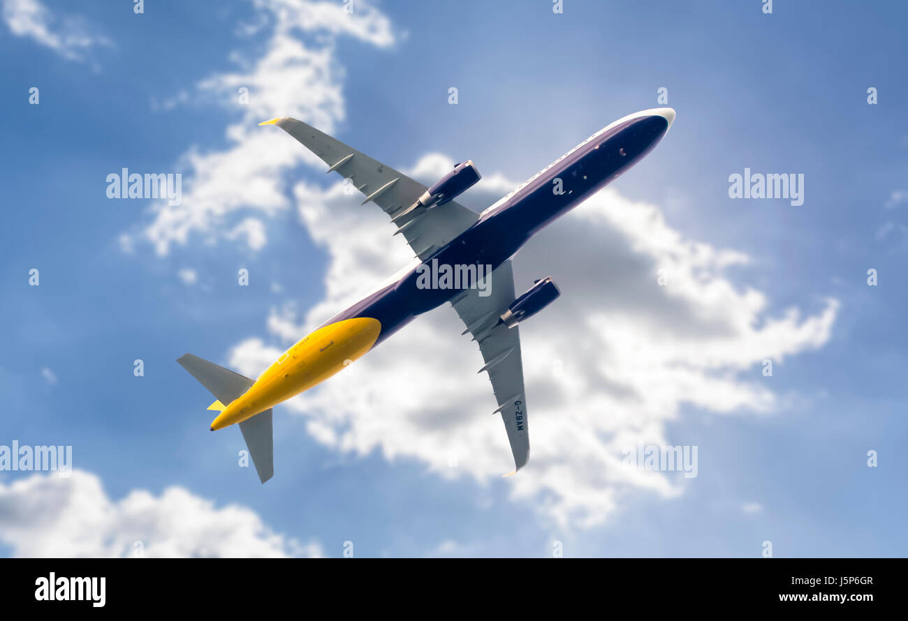 Passenger jet aeroplane flying low under clouds. Underside of plane. Aircraft underside. Plane travel concept. Air travel concept. Travelling by plane. Stock Photo