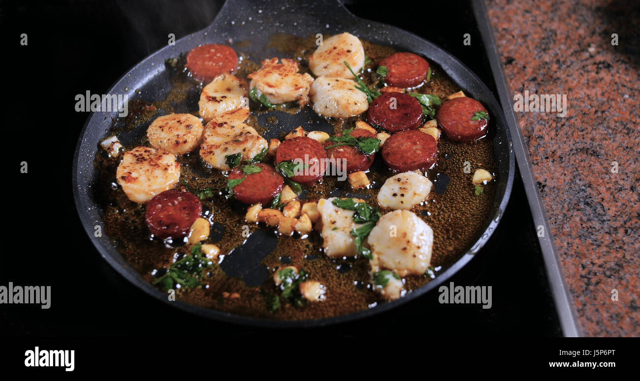 Frying scallops with chorizo, garlic and parsley Stock Photo