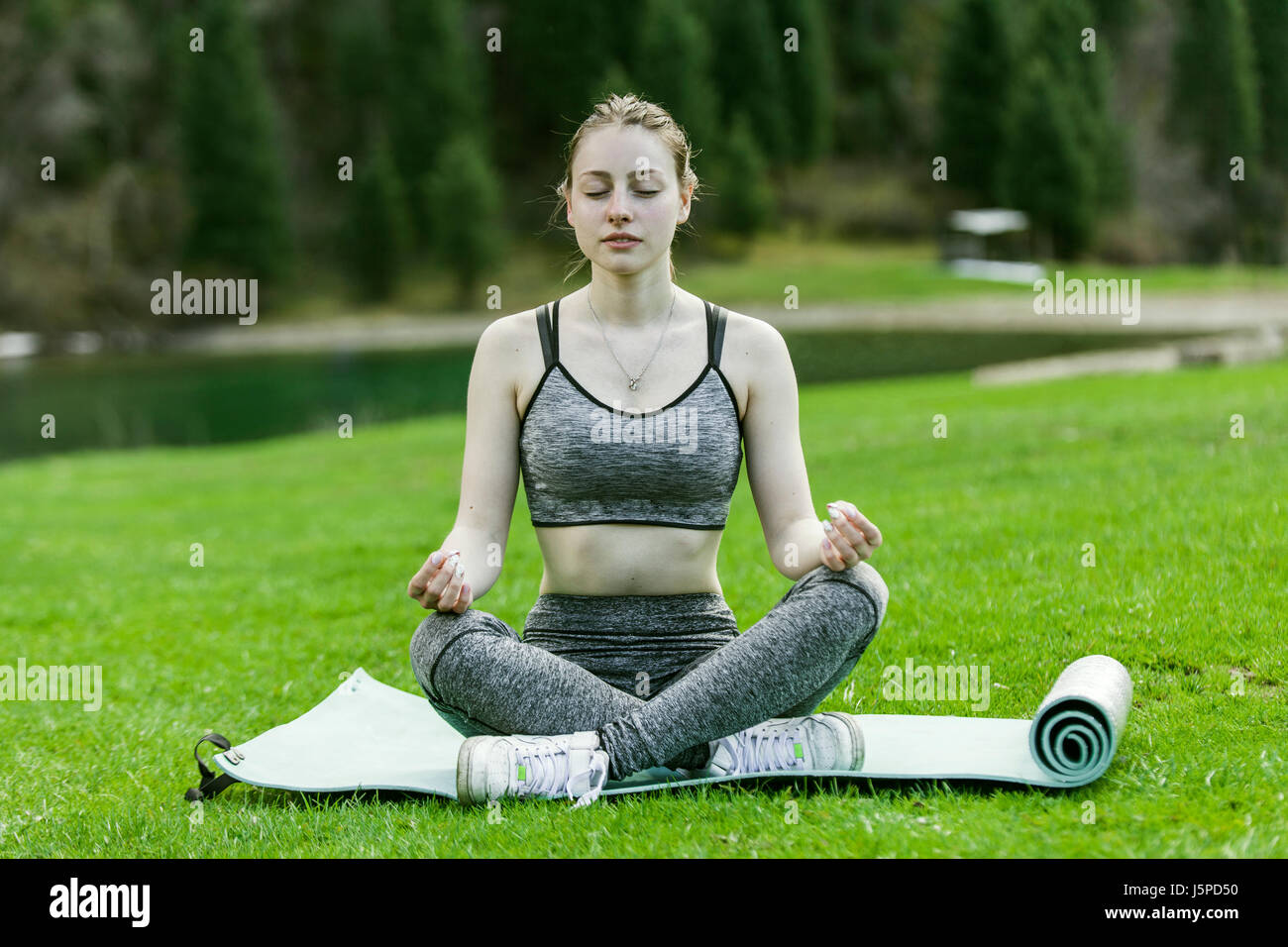 The girl meditates, sits on a rug on a green lawn Stock Photo - Alamy