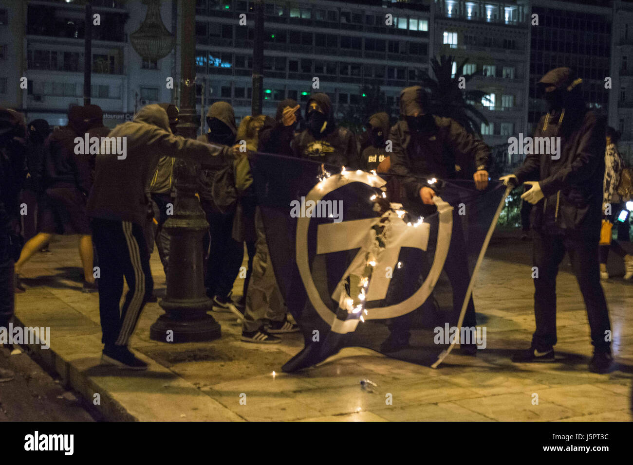 Athens, Greece. 18th May, 2017. Anarchists burn Alpha Bank's flag. A large demonstration was staged outside the parliament to protest over new austerity measures that were to be voted for by lawmakers at the same time. Credit: Nikolas Georgiou/ZUMA Wire/Alamy Live News Stock Photo