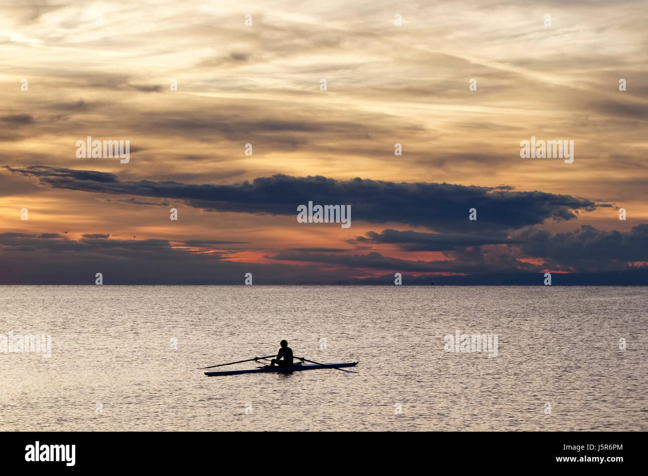 Sport. Solitary rower during his training session in the sunset light. Stock Photo
