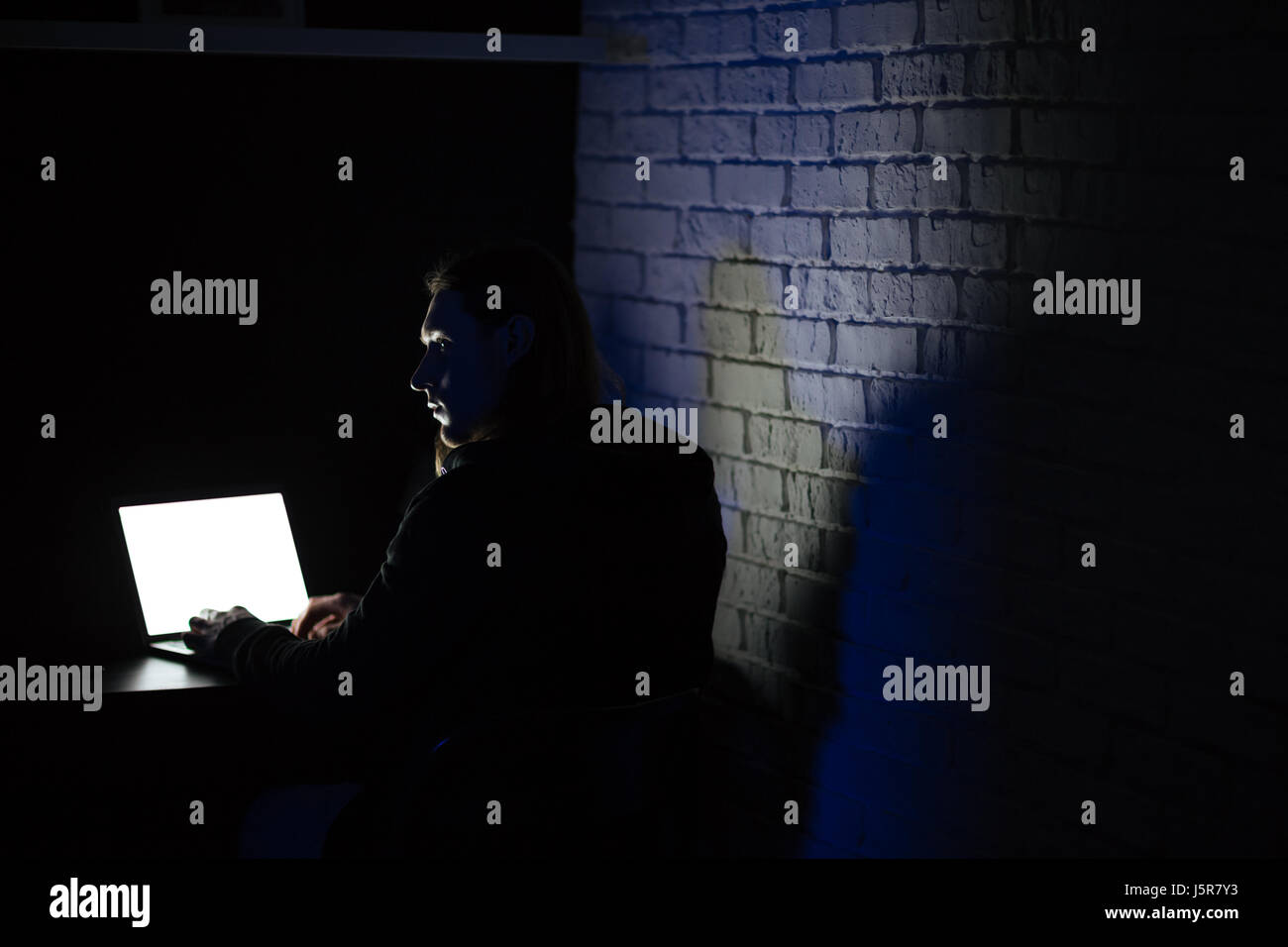 Back view photo of young serious man using laptop computer at home ...