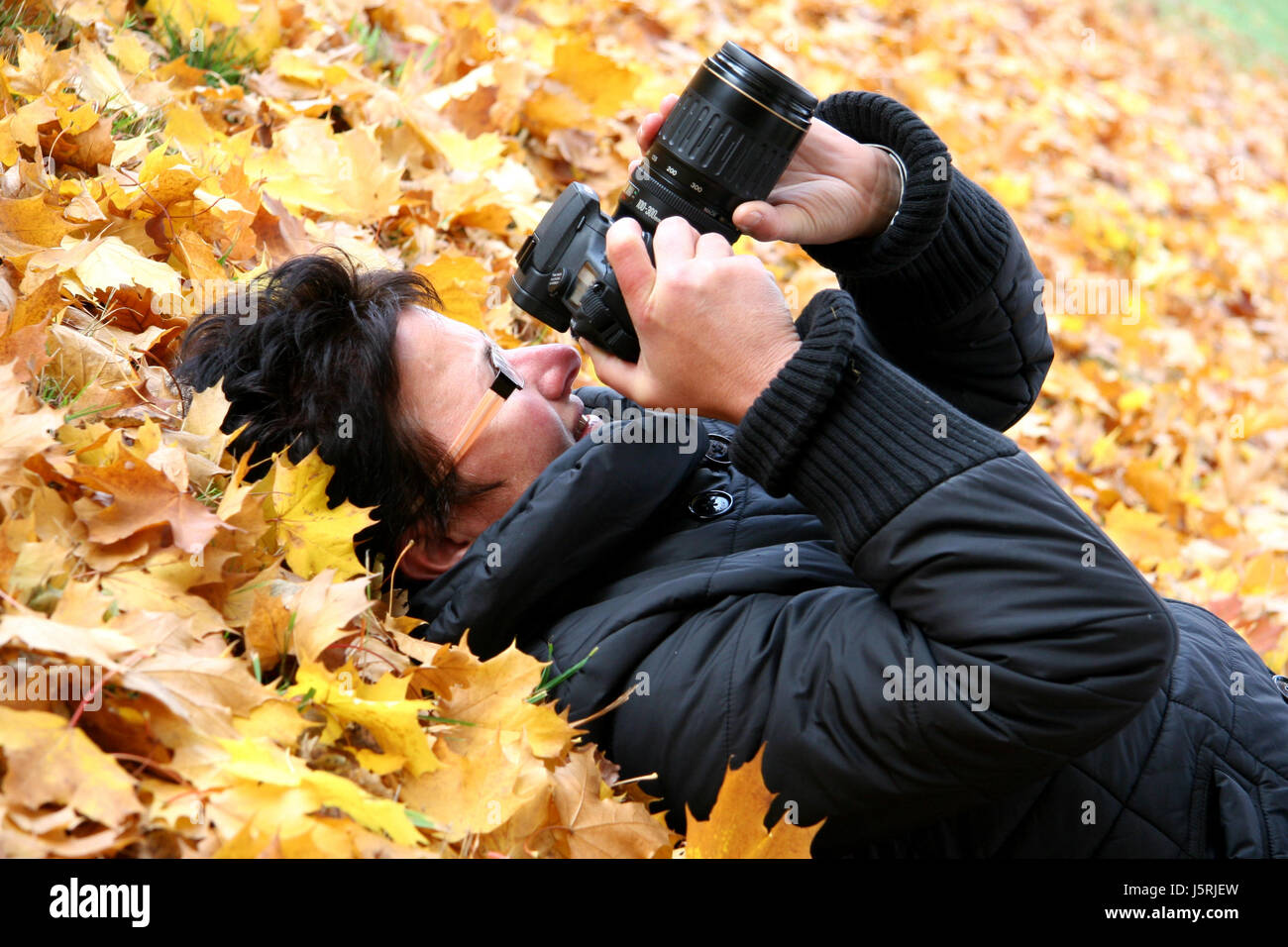 woman lying in leaves 3 - photographing Stock Photo