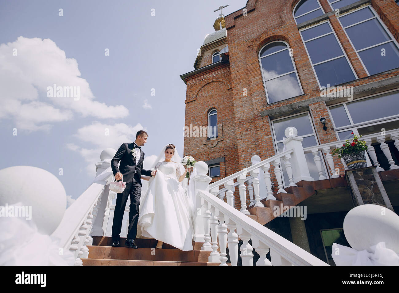 the bride and groom stand near the big house and windows Stock Photo ...