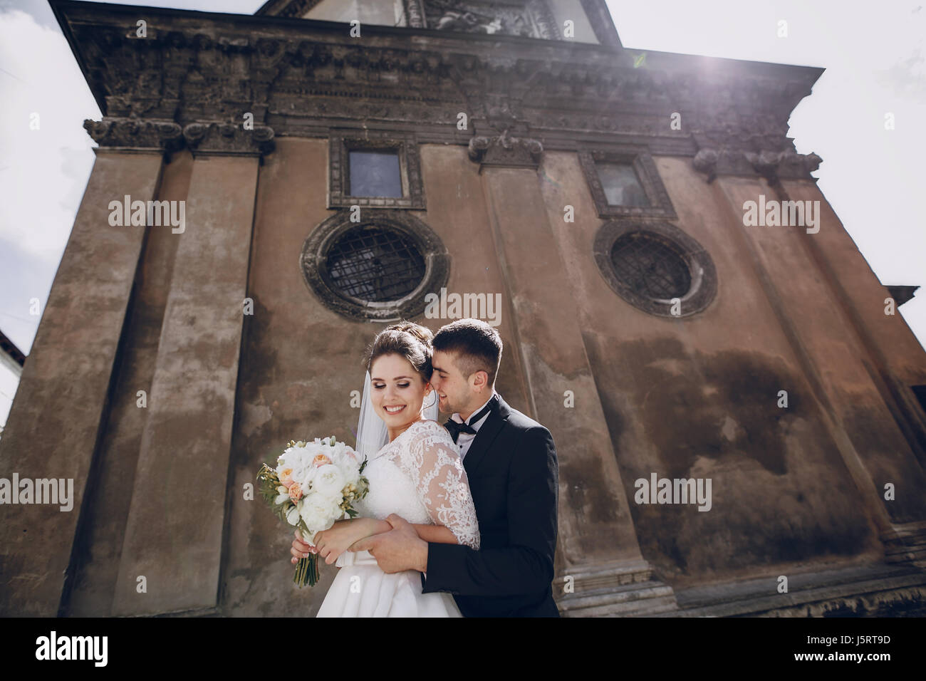 bride and groom standing near the old brown house Stock Photo - Alamy