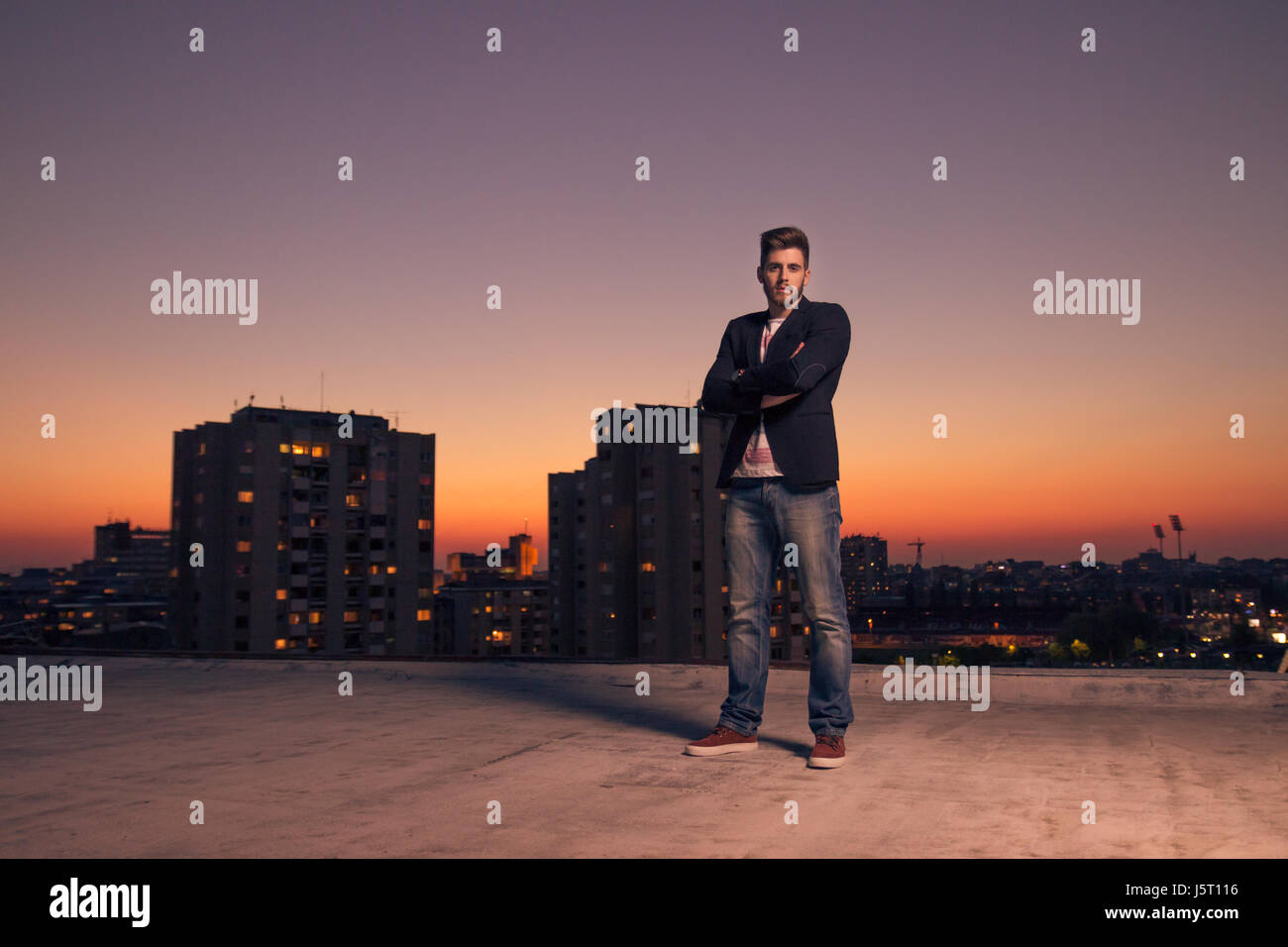 Sunset Sunrise, one young adult man only, rooftop roof, city lights, outdoors Stock Photo