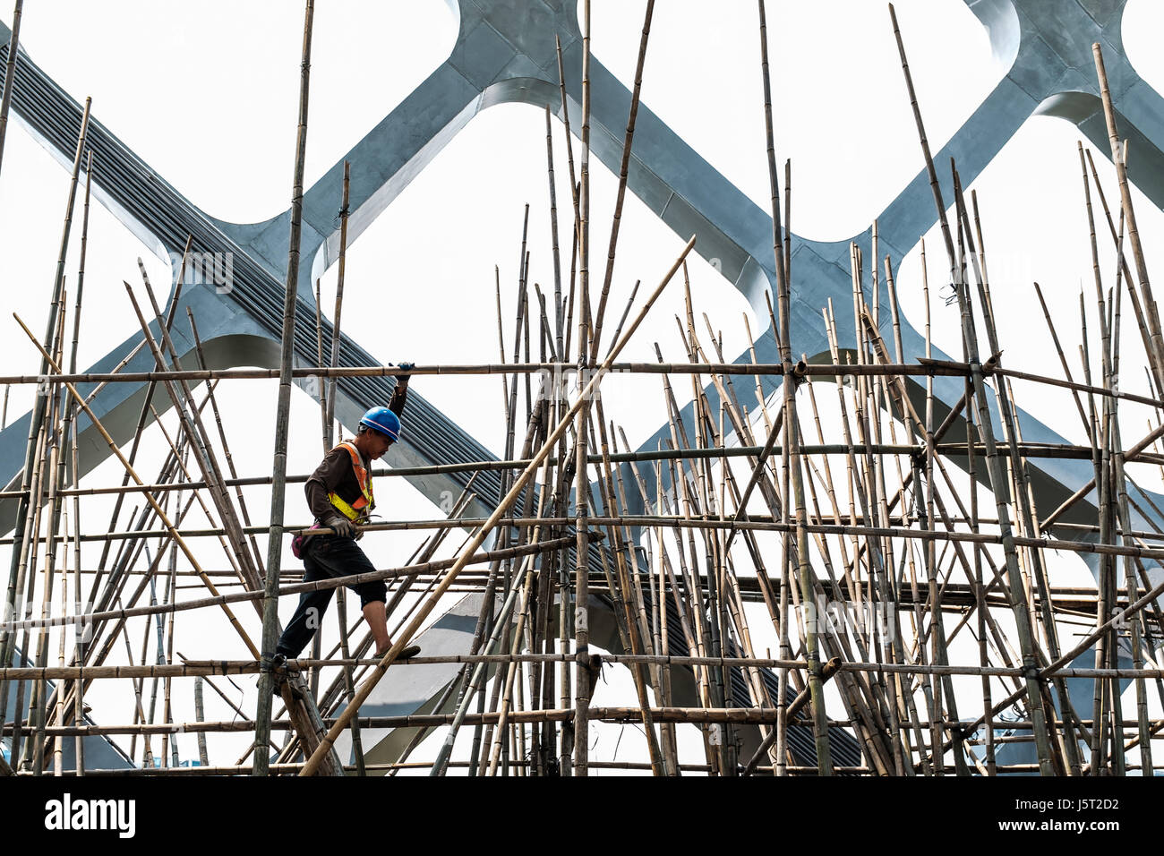 Shenzhen Bay Sports Centre, China, unrecognisable man walks on bamboo scaffolding. Stock Photo